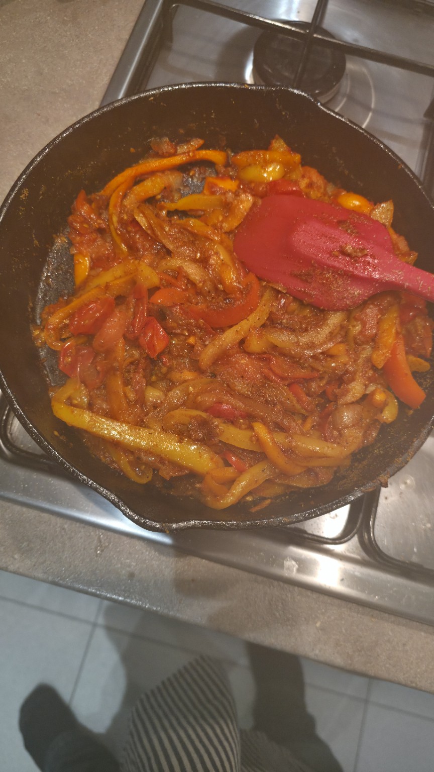 A rich orange-red smoky tomato and pepper mixture with spices in a black cast-iron pan