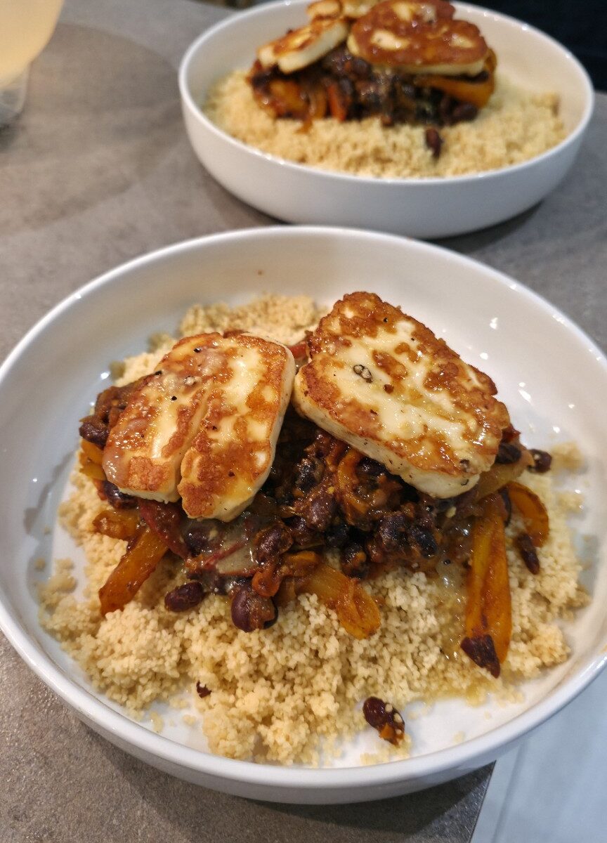 Golden pan-fried halloumi on smoky black beans, peppers and couscous in a white bowl, photographed in Jimmy's kitchen