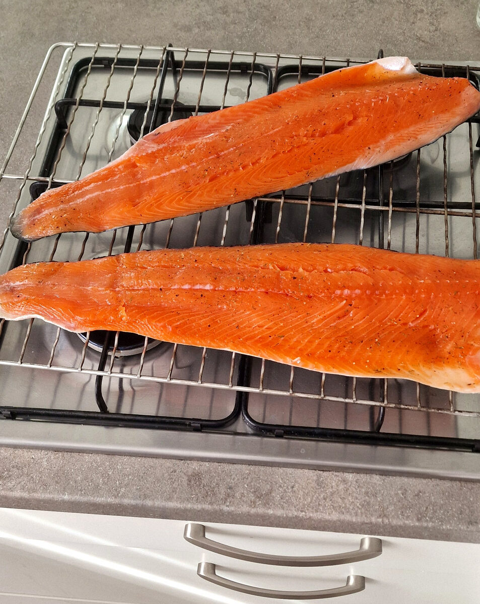Two hot-smoked salmon sides with orange flesh resting on a wire rack