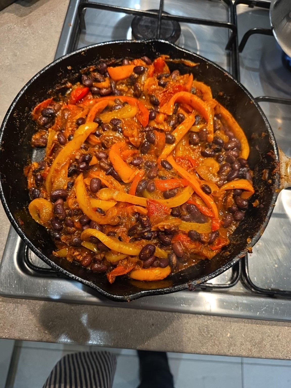 Black beans and colourful peppers in smoky tomato sauce in a cast-iron frying pan