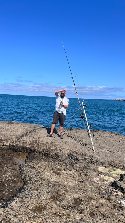 On the Anglesey rocks with my sea bass catch, fishing rods and a broad view of the sea and sky
