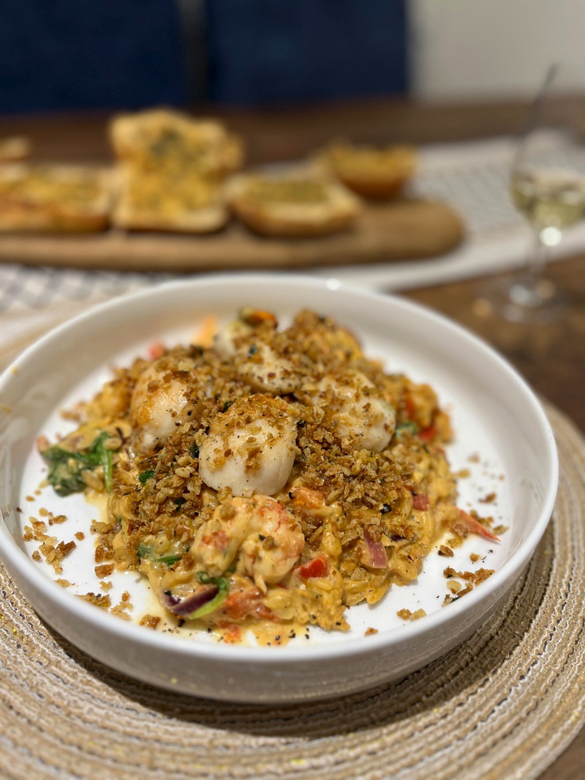 The finished baked feta and prawn orzo, served with seared scallops and crisp crumbs
