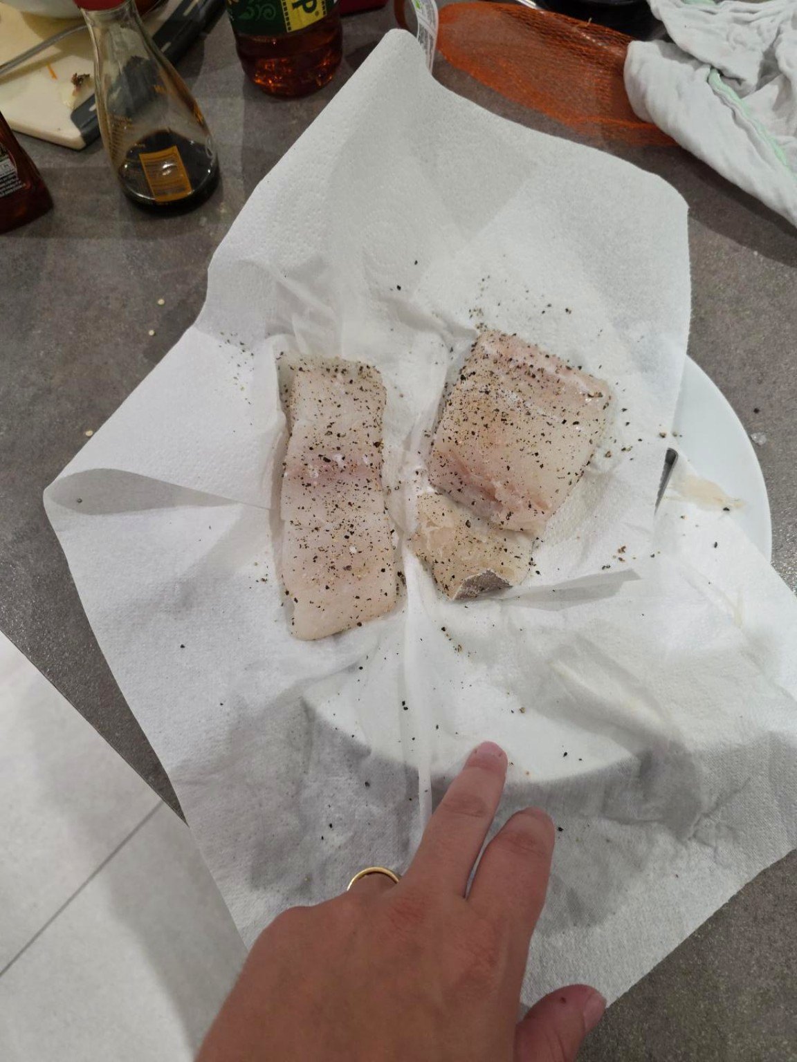 Two raw cod fillets patted dry on white kitchen paper