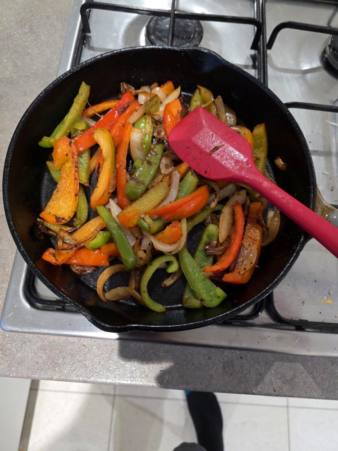 Sliced coloured peppers cooking in a black cast-iron pan