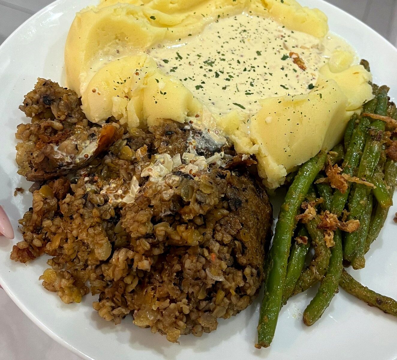 Homemade haggis served with buttery mashed potato, creamy whisky-onion sauce and green beans on a white plate