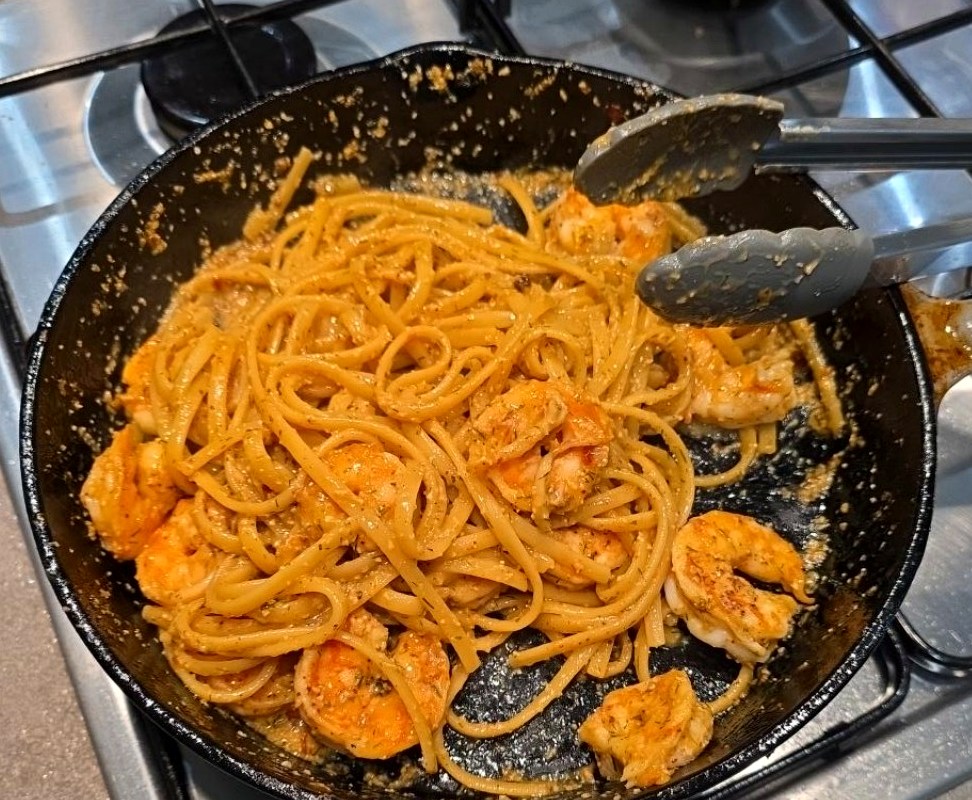 The white-wine prawn linguine tossed together in the cast iron frying pan with stainless steel tongs