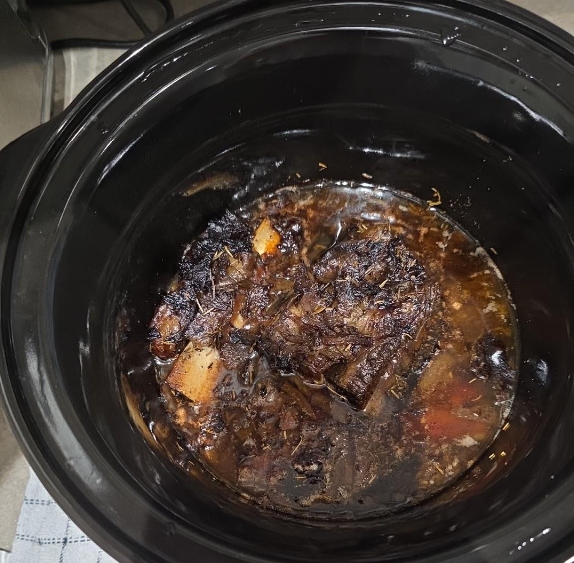 Wagyu beef short ribs in the slow cooker after eight hours, tender and separated from the bone